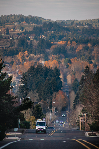 Aerial view of Sherwood, Oregon street running through a community amid rolling hills with fall foilage 