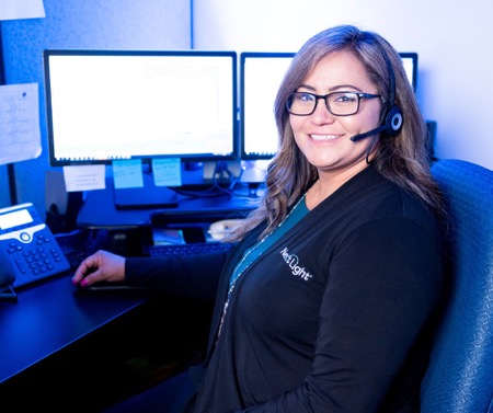 Longmont NextLight rep A smiling customer service rep sits in front of her workstation