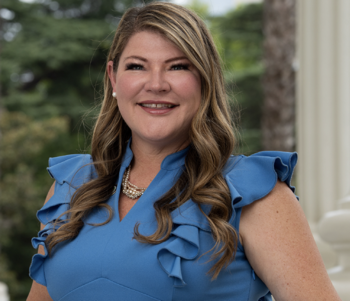 CA Assembly member Tasha Boerner smiles at camera wearing a light blue sleeveless dress with ruffles  