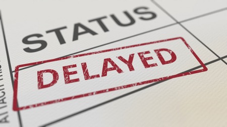 A document is stamped: "Status Delayed" with "delayed" written in red ink