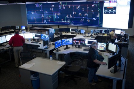 An operations center that looks like NASA's Houston Control with a roomful of desks in front of a large wall monitor with multiple screens