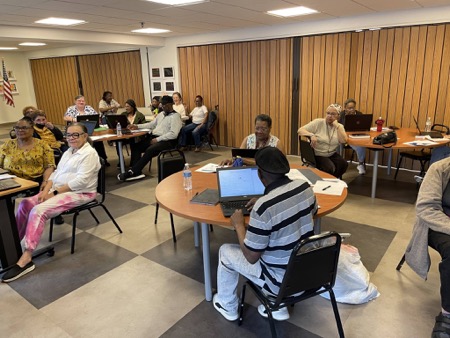 About two dozen mostly older adults seated around tables in digital skills class as part of the Click program