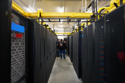 Three Hoopa Valley PUD fiber techs stand at the end of a row of black server racks
