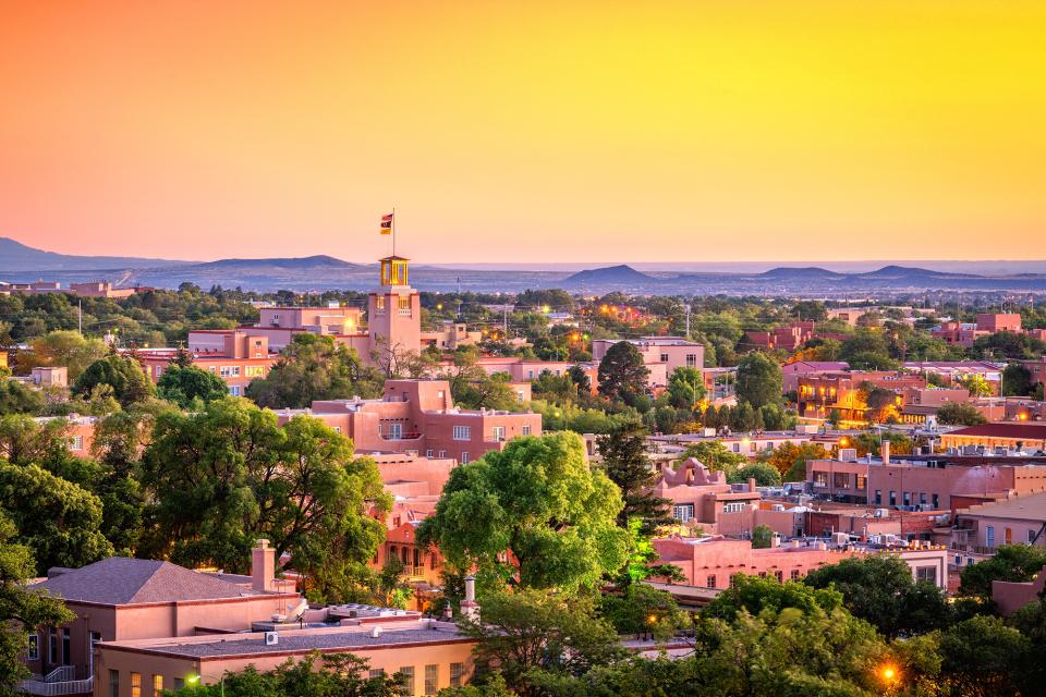 An aerial view of a city in New Mexico at dusk with a picturesque mountain scape in the background