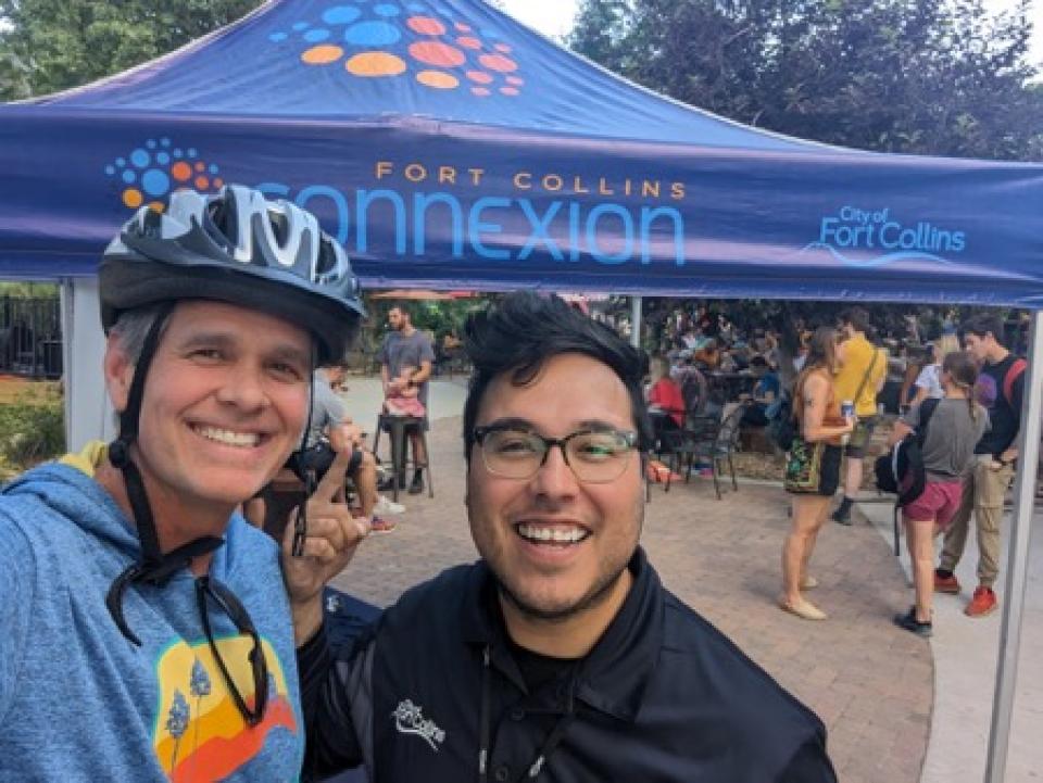 Two happy subscribers smile at town event under a Fort Collins Connexion tent