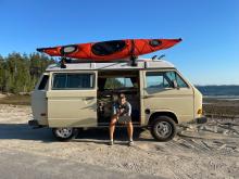 MCA President Andrew Butcher sits in side door of his yellow Volkswagen van with red canoe on roof